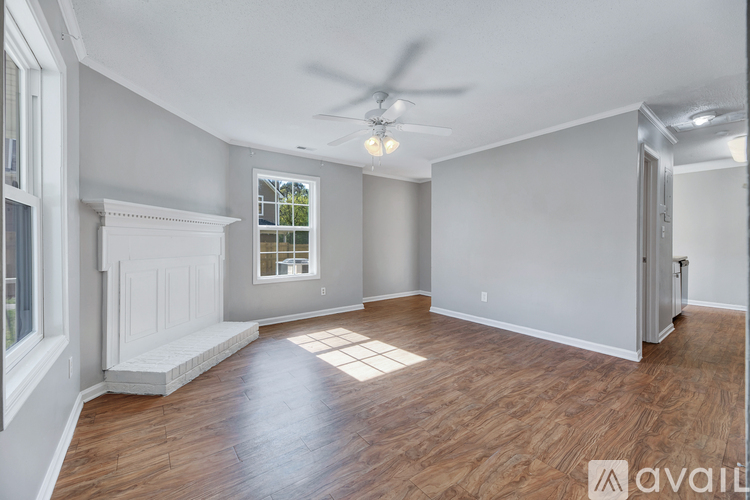 A spacious room with wood flooring and a ceiling fan.