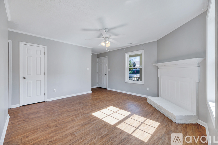 A room with a ceiling fan and a window showing a view of a house.
