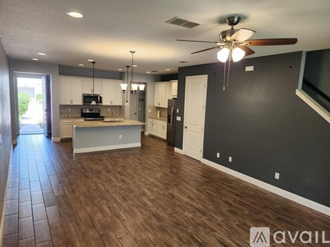A spacious living room with a ceiling fan and hardwood flooring.