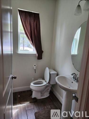 A bathroom with a toilet, sink, and window.