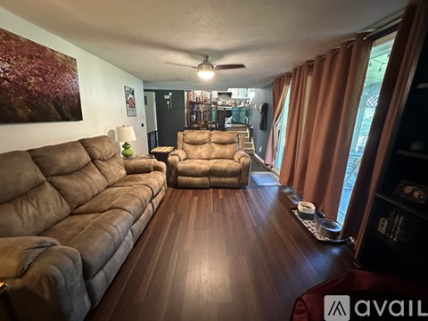A living room with a long brown couch and a brown chair.
