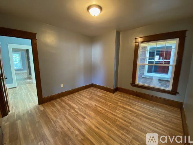 A room with wooden flooring and a window with a view of a building.