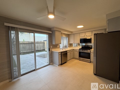 A kitchen with a refrigerator on the right and a dining table in the middle.