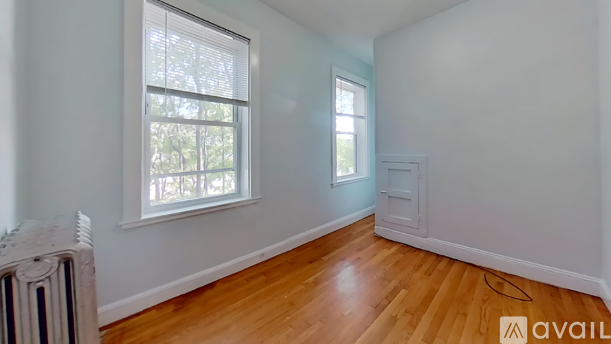 A room with wooden floors and a window with blinds.