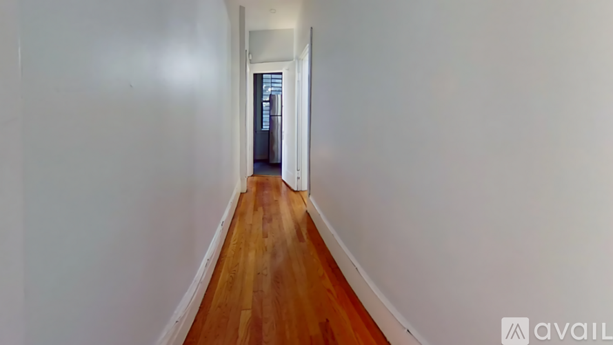 A long hallway with wooden floors and white walls.