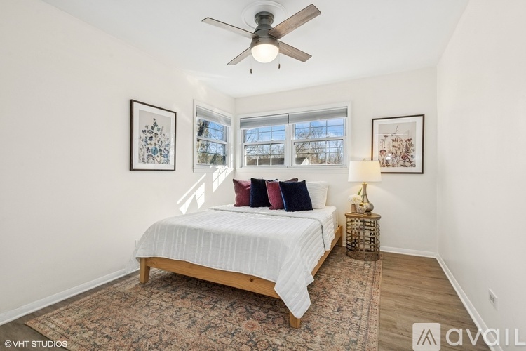 A bedroom with a bed, a ceiling fan, and two pictures on the wall.
