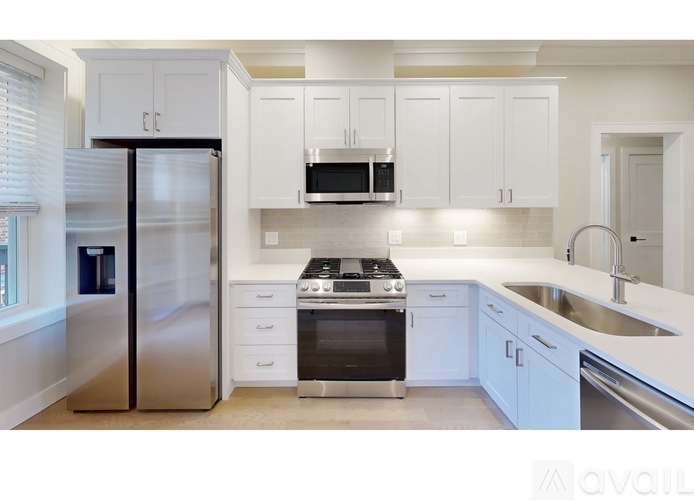 A modern kitchen with white cabinets and stainless steel appliances.