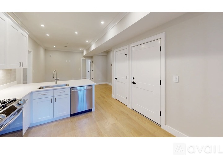 A modern kitchen with white cabinets and a wooden floor.