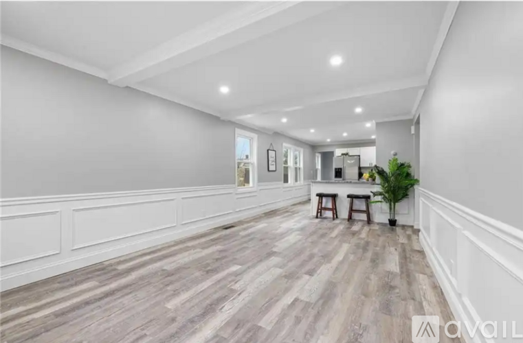 A spacious room with wooden flooring and white walls.