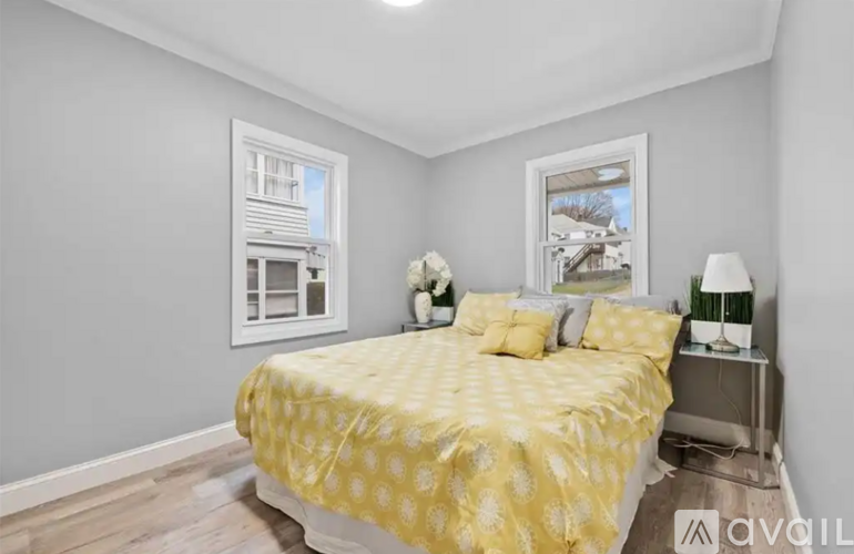 A bedroom with a bed covered in yellow bedding and a nightstand with a lamp.