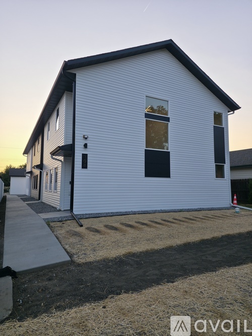 A white house with a black roof and a small porch.