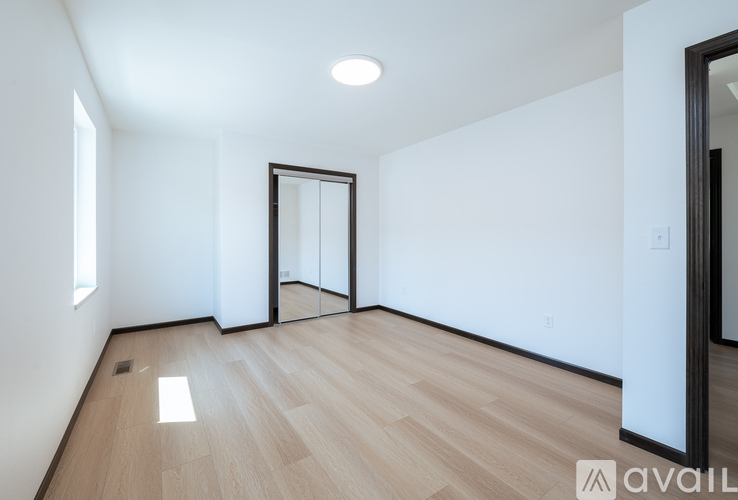 A spacious room with wooden flooring and white walls.