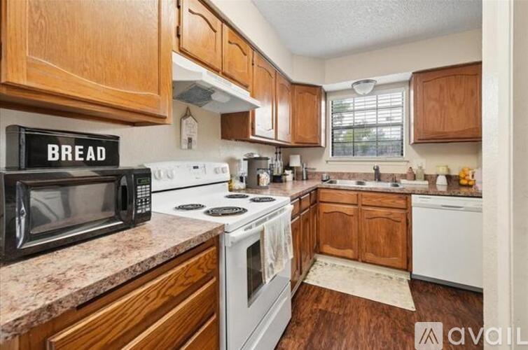 A kitchen with wooden cabinets and a black microwave above the stove.