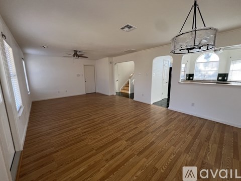 A spacious room with wooden flooring and a hanging light fixture.