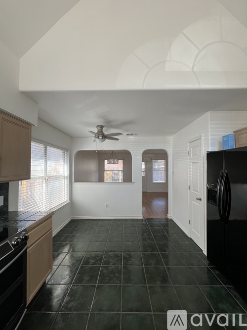 A kitchen with black tile flooring and wooden cabinets.