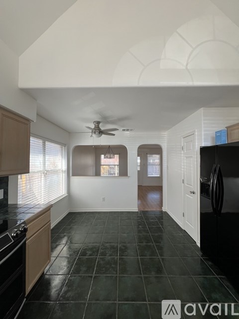 A kitchen with black tile flooring and wooden cabinets.