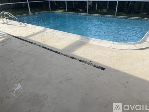 A pool with a concrete edge and a metal ladder.