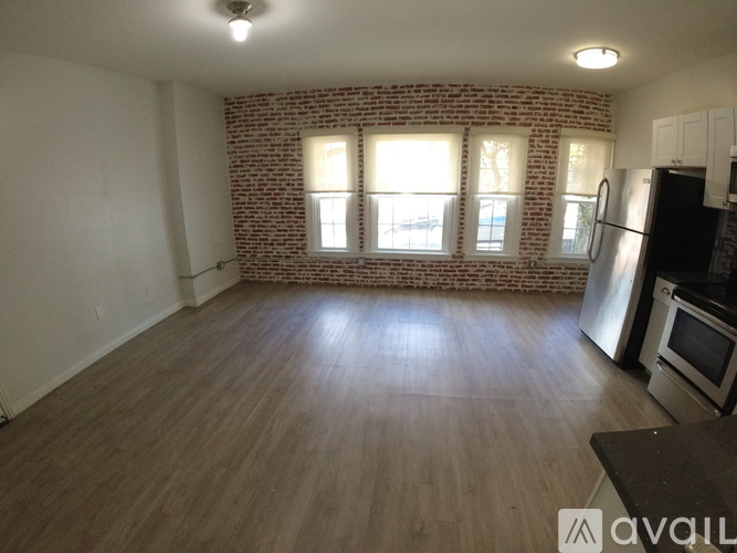 A kitchen with a brick wall and wooden floors.