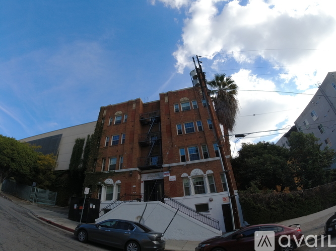 A car is parked on the side of a street in front of a brick building.