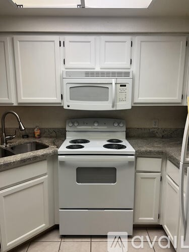 A white kitchen with a stove, sink, and microwave.