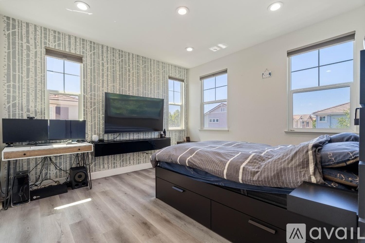 A bedroom with a large bed, a television, and a desk with a computer setup.