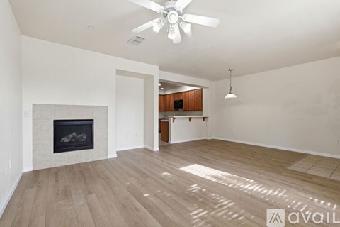 A spacious room with a fireplace and wooden flooring.