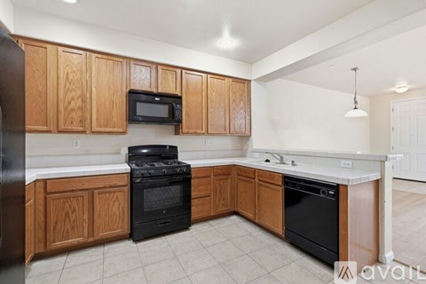 A kitchen with wooden cabinets and black appliances.