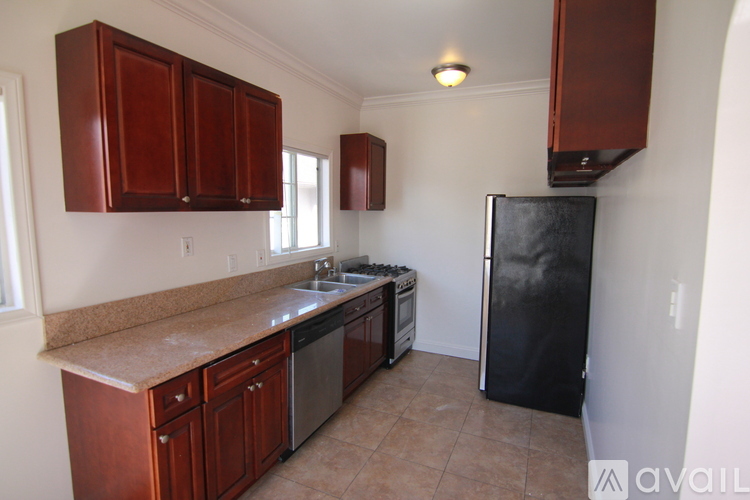A kitchen with brown cabinets and a black refrigerator.