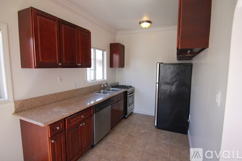 A kitchen with brown cabinets and a black refrigerator.