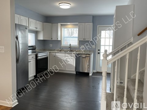 A kitchen with white cabinets and a stainless steel refrigerator.