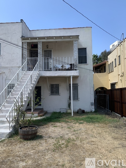 A white two-story house with a balcony and stairs leading to the second floor.