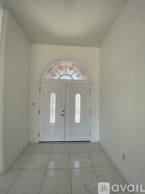 A hallway with a white door and a window above it.