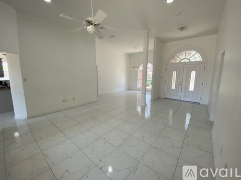 A spacious room with a fan and marble flooring.