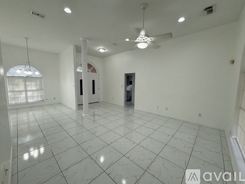 A spacious room with white marble flooring and a ceiling fan.