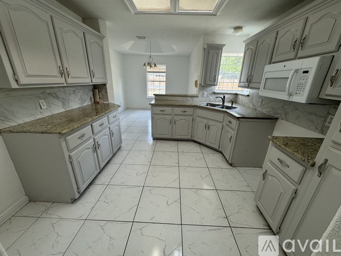 A kitchen with white cabinets and a marble countertop.