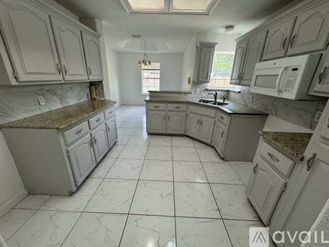 A kitchen with white cabinets and a marble countertop.