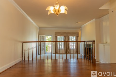 A large, empty room with wooden floors and a chandelier hanging from the ceiling.