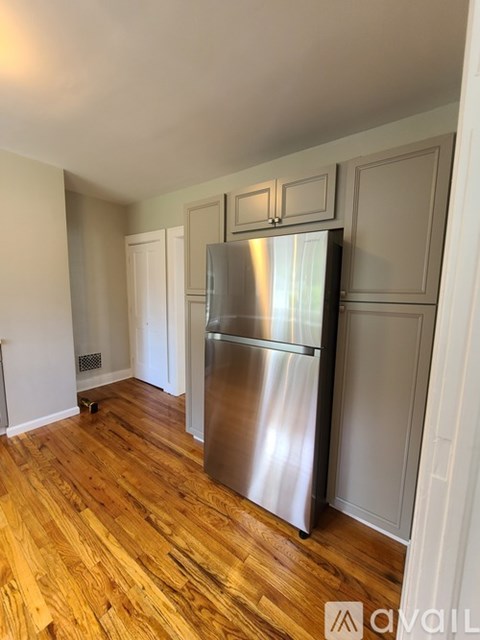 A kitchen with a stainless steel refrigerator and wooden floors.