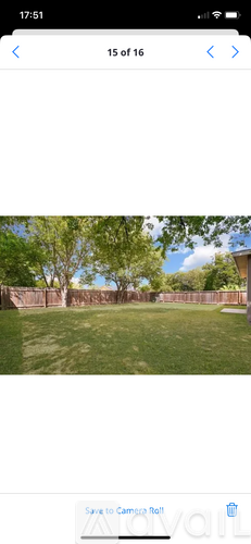 A grassy area with a fence and trees in the background.