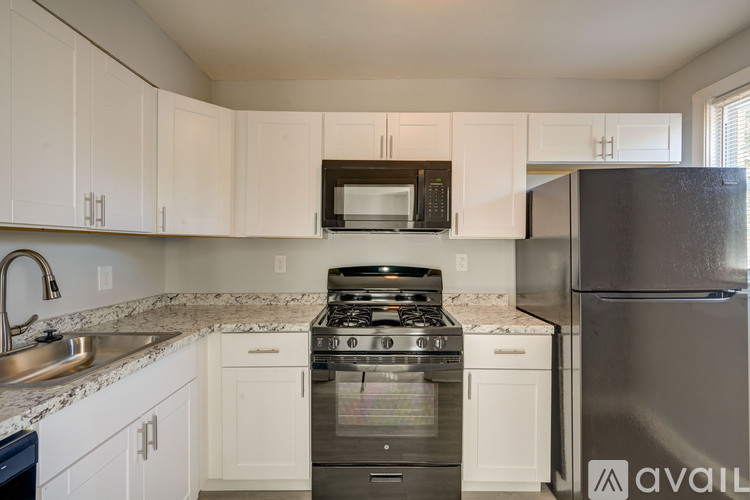 A kitchen with white cabinets and a black refrigerator.