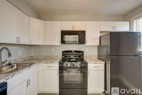 A kitchen with white cabinets and a black refrigerator.