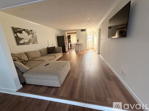 A living room with a couch and a television on the wall.
