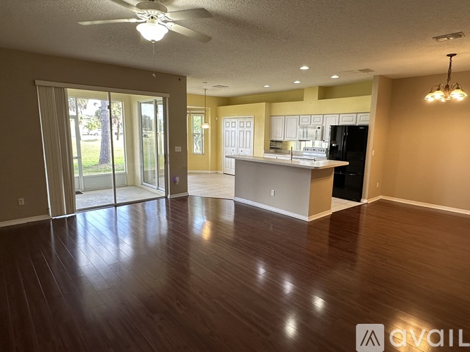 A spacious living room with a kitchen in the background.