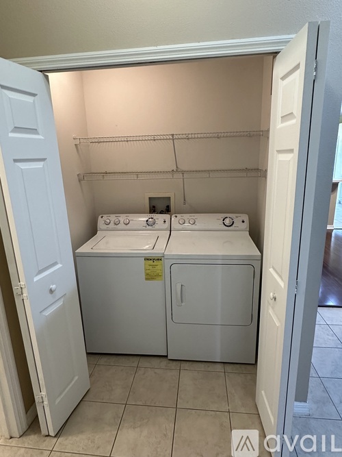 A white washer and dryer are in a small, white-walled laundry room.