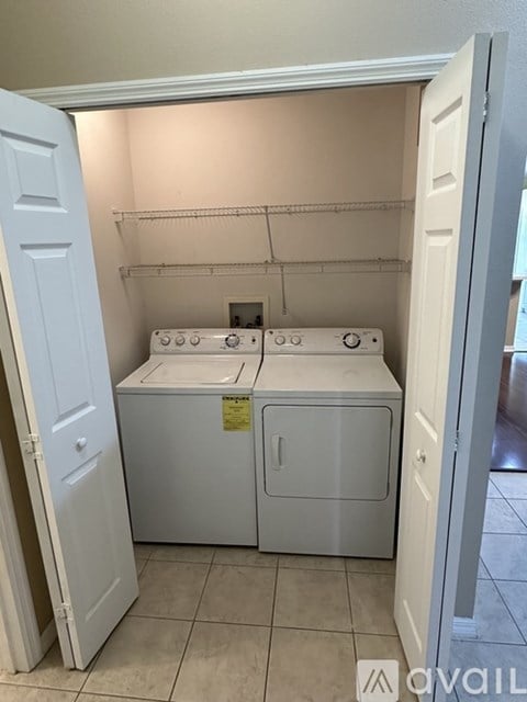 A white washer and dryer are in a small, white-walled laundry room.
