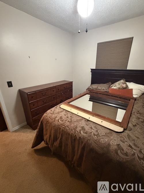 A bedroom with a bed, dresser, and window with blinds.