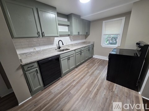 A kitchen with wooden floors and green cabinets.