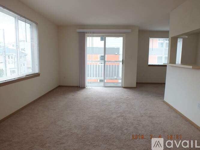 A room with a carpeted floor and a large window overlooking a building.