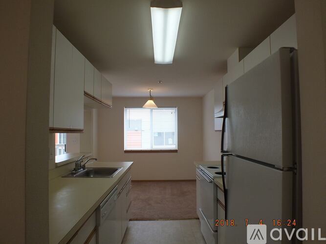 A kitchen with a refrigerator, sink, and window.