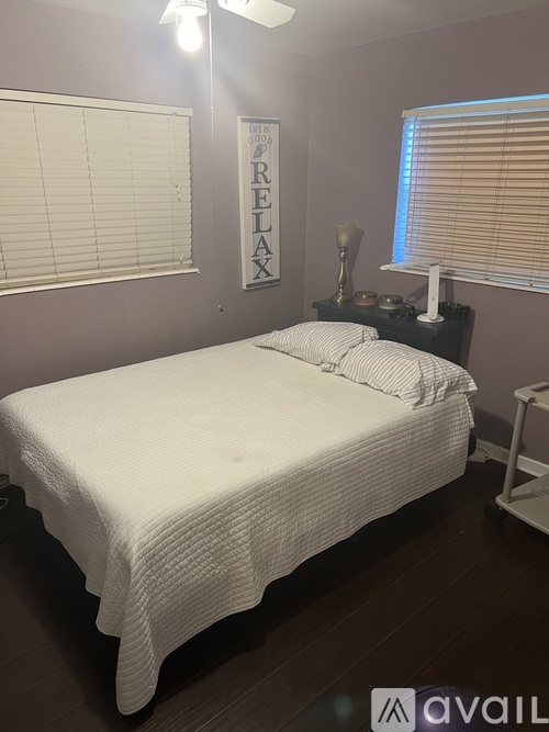 A bedroom with a bed, nightstand, and a poster on the wall.